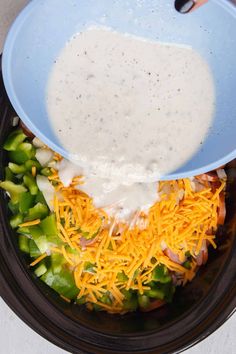 a blue bowl filled with cheese and vegetables