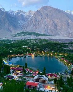 an aerial view of a town and lake surrounded by mountains in the evening with lights on