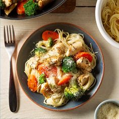 two plates of pasta with chicken, broccoli and carrots