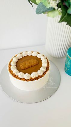 a white cake sitting on top of a table next to a vase filled with flowers