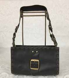 "Here we have a vintage brown leather footed Purse with a wide strap, metal studs and large buckle. This has a great retro look. This is in very nice condition considering its age. I noticed some light scratches but no ther problems. It measures: Height - 6\" Width - 9 3/4\" Depth - 4 1/4\" Strap Drop - 11 1/4\" I try my best to give accurate descriptions, although I am no expert, plus I'm human and sometimes I might miss a flaw. I always provide high resolution photos and consider them to be pa Vintage Brown Leather Shoulder Bag With Brass Hardware, Vintage Leather Bags With Metal Hardware, Leather Satchel Shoulder Bag With Rivets, Retro Leather Shoulder Bag With Metal Hardware, Brown Leather Shoulder Bag With Buckle Closure, Vintage Distressed Brown Leather Shoulder Bag, Brown Leather Bags With Rivets, Brown Leather Bags With Hardware, Leather Shoulder Bag With Rivets For Daily Use