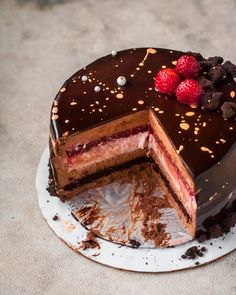 a chocolate cake with raspberries on top and one slice missing from the cake