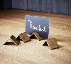 three pieces of metal sitting on top of a wooden table next to a sign that says rachel