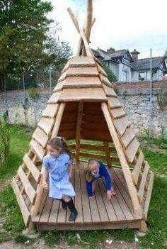 two young children playing in a wooden teepee