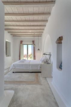 a bedroom with white walls and carpeted flooring next to a doorway leading to a bed