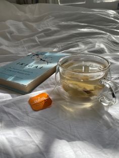 a cup of tea next to a book on a bed