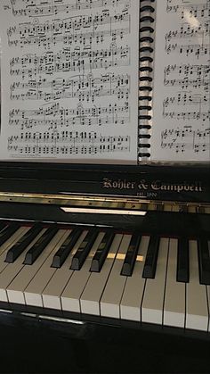 a piano with sheet music on it sitting in front of a keyboard that is black and white