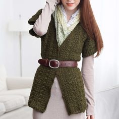 a woman wearing a green cardigan and white shirt is standing in front of a couch