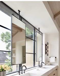 a bathroom with double sinks and large mirrors on the wall next to it's windows