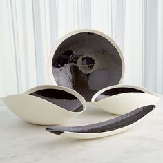 three white bowls sitting on top of a table next to a black and white plate