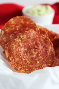 three sausage patties on a white plate with dipping sauces in the back ground