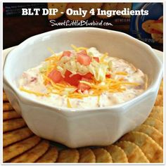 a white bowl filled with dip and cheese on top of crackers next to chips