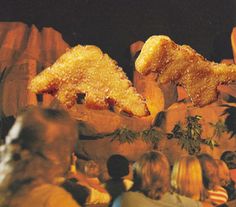 some people are standing in front of two large pieces of food that look like mountains