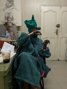 a woman sitting in a chair with a green hat on her head and holding a small bird