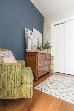 a living room with blue walls and wooden furniture in the corner, including a green chair