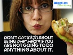 a woman with glasses eating a sandwich in front of her face and looking at the camera