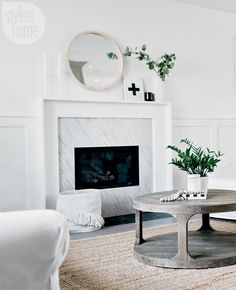 a living room with a white couch, coffee table and fireplace