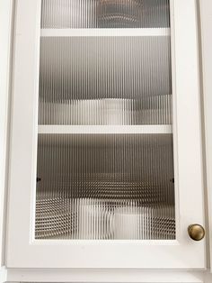 a white cabinet with glass doors and knobs