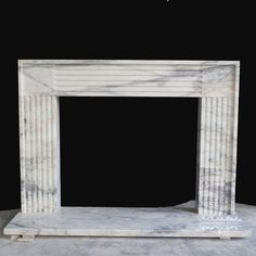 a white marble fireplace with columns on the top and bottom, against a black background