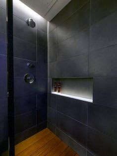 there is a shower in the bathroom with wood flooring and glass doors on the wall