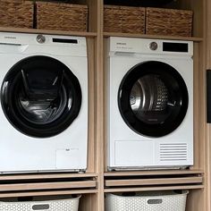 two washers sitting next to each other in front of wooden shelves with baskets on them