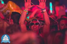 a group of people with their hands up in the air at a music festival or party