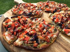 a pizza sitting on top of a wooden cutting board next to a green grass covered field