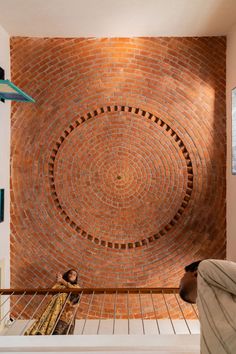 a person sitting on a bench in front of a brick wall with an artistic design