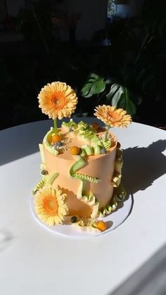 a cake decorated with flowers on top of a white tableclothed table cloth, in the sun