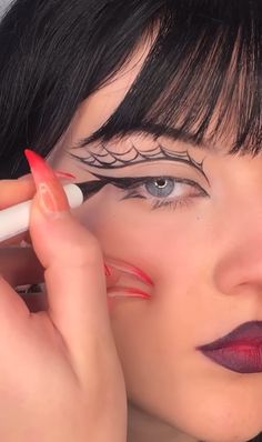 Uma mulher branca fazendo um delineado que imita uma teia de aranha com batom vermelho e preto Halloween Eyeliner Ideas, Halloween Eyeliner, Goth Eye Makeup, Funky Makeup, Indie Makeup, Halloween Eye Makeup, Halloween Makeup Inspiration, Swag Makeup, Alternative Makeup