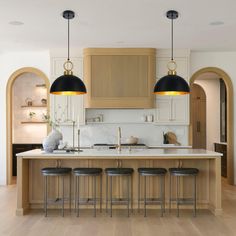 a kitchen with two black lights hanging over the island and stools next to it