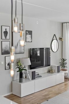 a living room with white furniture and lots of pictures on the wall, including a flat screen tv