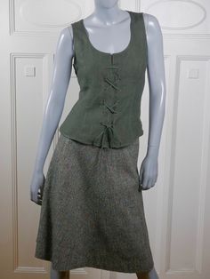 This 1990s German vintage sage green linen vest has a scoop neckline and features a corset-style crisscross lacing in the front. The lightweight vest has a zipper running the full length of the left side, which makes dressing an ease. Bust = 34 inches (86.36cm) Shoulder width = 15.5 inches (39.37cm) Waist = 30 inches (76.2cm) Hemline = 39 inches (99.06cm) Vest Length = 20.5 inches (52.07cm) Brand label: Country Line (Germany) Size: 6 US, 10 UK Material: 100% Linen Condition: Near Mint (Like New Silver Evening Dress, 30 Inch Waist, Linen Vest, Lightweight Vest, Vintage Midi Dresses, Green Tweed, Sleeveless Tops Summer, Blue Green Orange, Heather Green