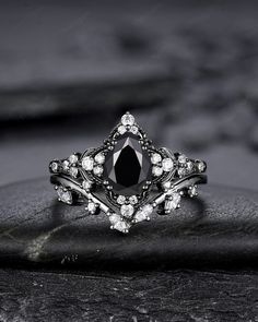 a black and white photo of a ring with diamonds on top of it, sitting on a rock