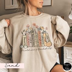 a woman wearing a sweatshirt with flowers and books on it