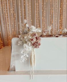 a bouquet of flowers sitting on top of a white box with string lights behind it