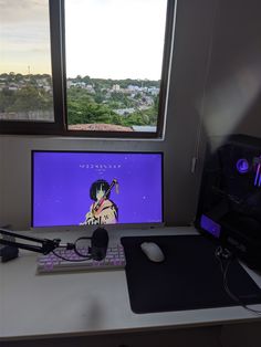 a computer monitor sitting on top of a desk next to a keyboard and headphones