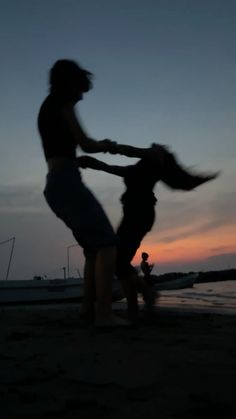 two people playing with a dog on the beach at sunset or dawn, in silhouette