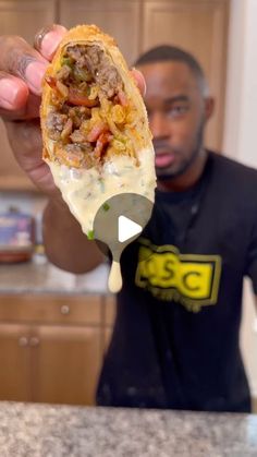 a man holding up a taco filled with meat and cheese