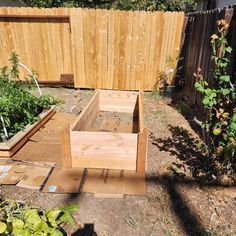 a wooden bench sitting in the middle of a yard next to a fence and garden