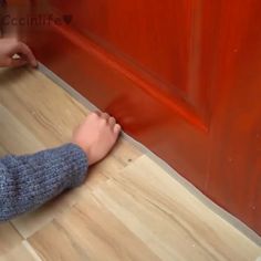 a child's feet on the floor next to a red door