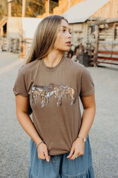 Saddle up with our Horsin' Around Tee. This vintage western t-shirt features a playful horses graphic in classic brown. With short sleeves and a classic fit, it's perfect for any rodeo or just horsin' around. Haylee is wearing size small paired with The Lodonna Skirt Casual T-shirt For Western-themed Fall Events, Fall Ranch Crew Neck T-shirt, Western Style T-shirt For Rodeo, Western-style T-shirt For Western-themed Fall Events, Western Style T-shirt For Fall Western-themed Events, Graphic Tee For Western-themed Fall Events, Country Style Short Sleeve T-shirt For Rodeo, Fitted Crew Neck T-shirt For Rodeo, Country Style Short Sleeve Tops For Western-themed Events