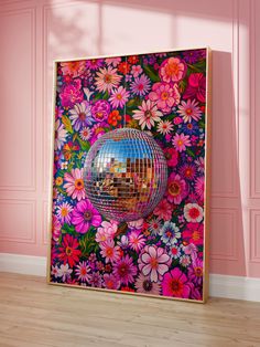 a mirror ball hanging from the side of a wall in front of pink walls and flowers