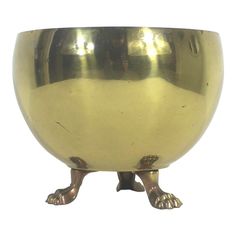 a shiny metal bowl with two legs and feet