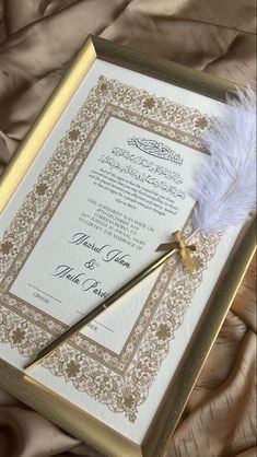 an ornate wedding card with a feather on it and a pen in the middle next to it