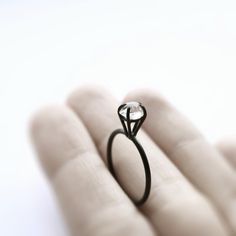 a close up of a person's hand holding a ring with a diamond on it