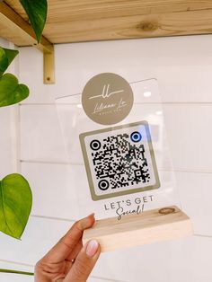 a person holding up a piece of wood with a qr code on it