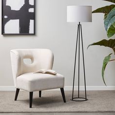 a white chair sitting next to a lamp on top of a floor