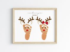 two reindeer handprints with red noses and antlers on them, framed in a wooden frame