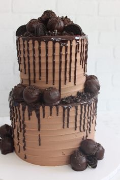 a three layer cake with chocolate icing drizzled on top and cookies